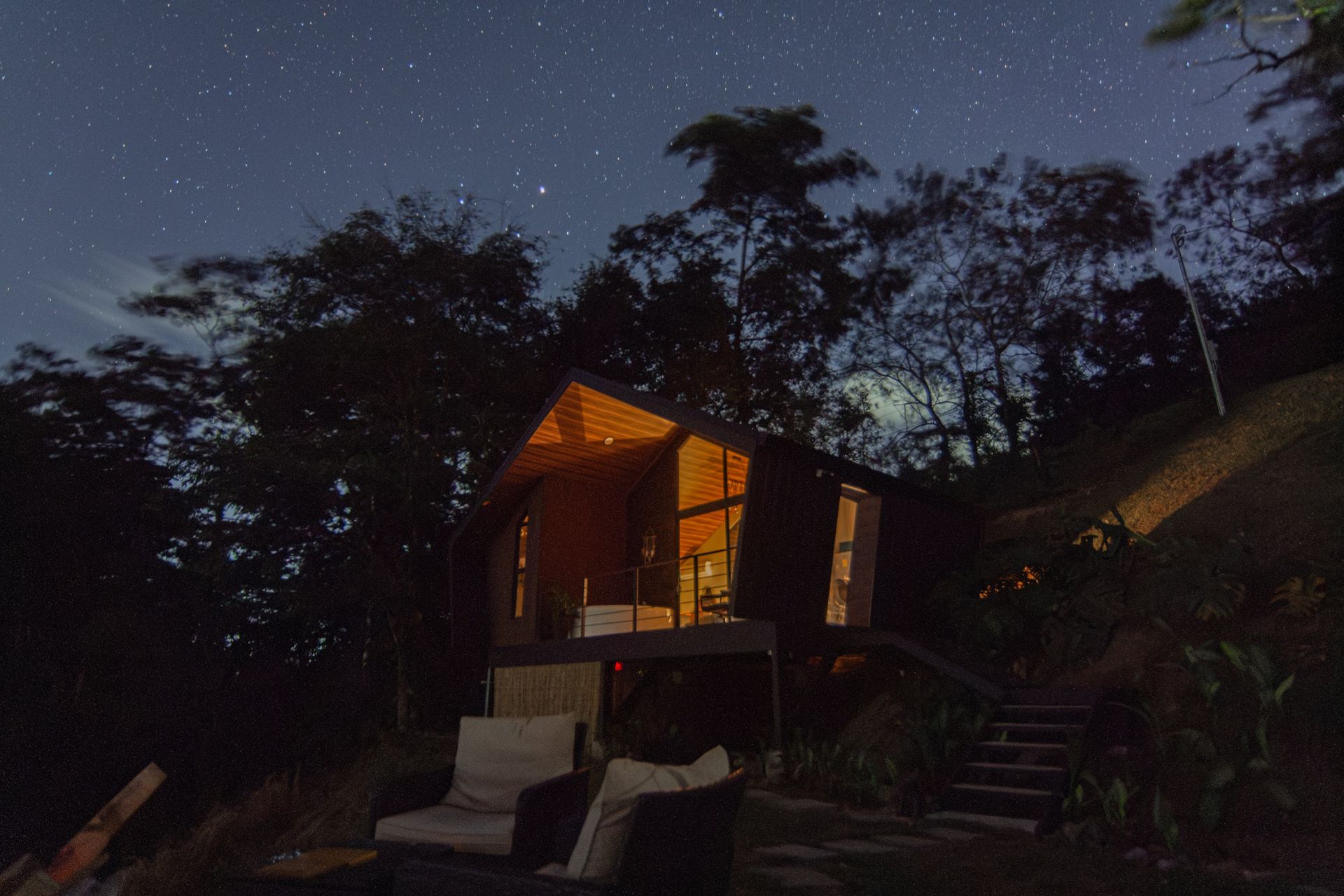 Cabaña iluminada bajo un cielo estrellado entre los árboles