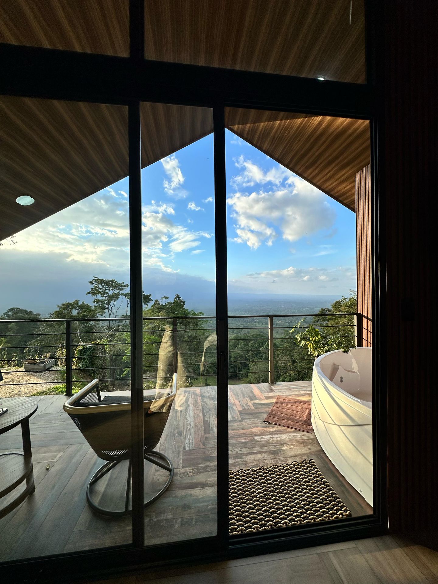 Vista desde el ventanal hacia el balcón con jacuzzi, el bosque y la llanura de San Carlos