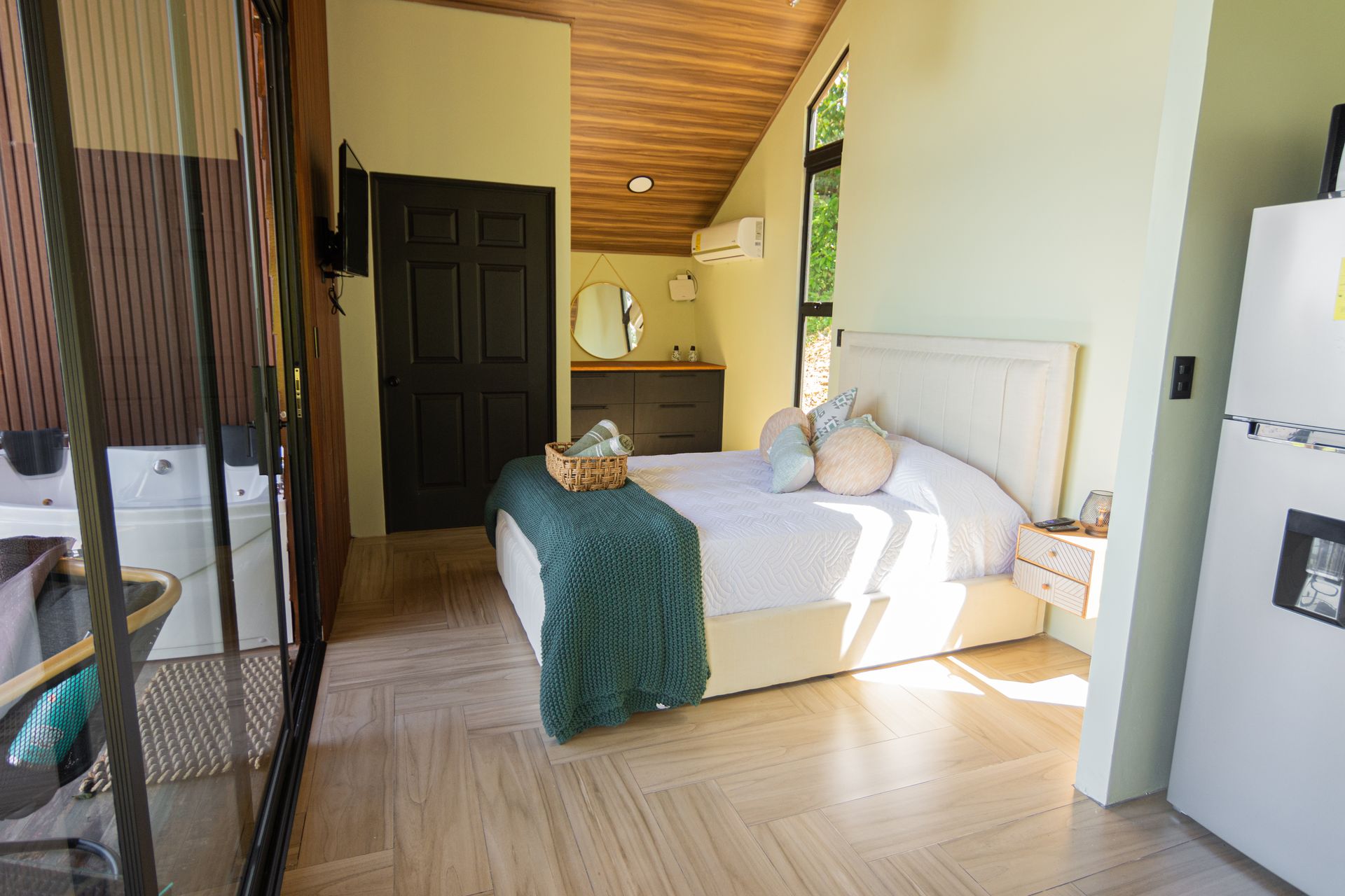Habitación luminosa de día con cama Queen y manta verde